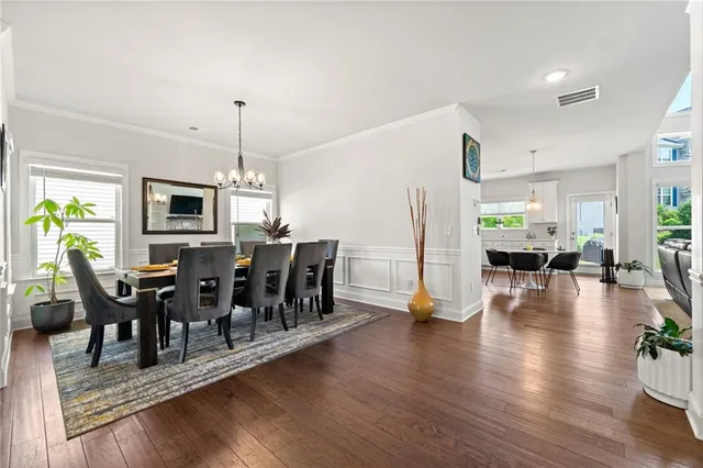 a view of a dining room and livingroom with furniture wooden floor a rug a fireplace and a chandelier