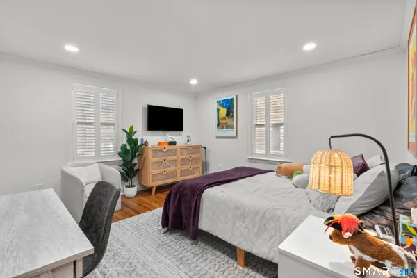 a bedroom with a bed a couch and a flat screen tv