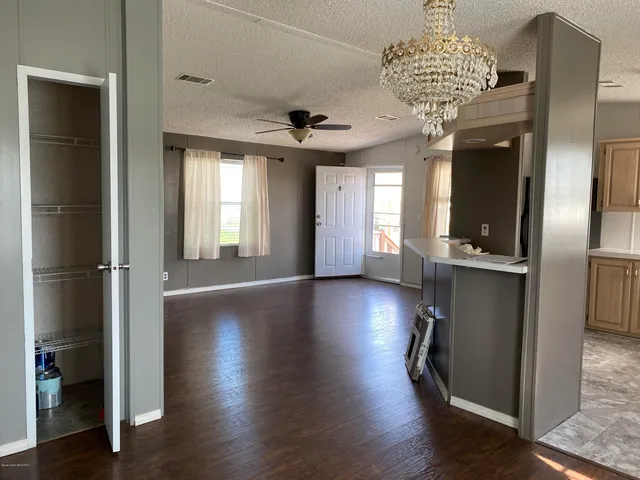 an empty room with wooden floor chandelier and windows