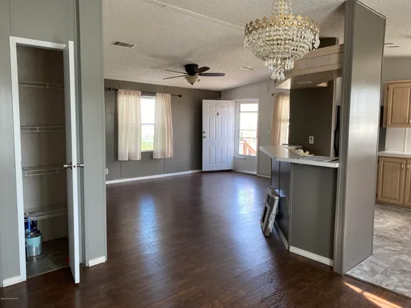 an empty room with wooden floor chandelier and windows