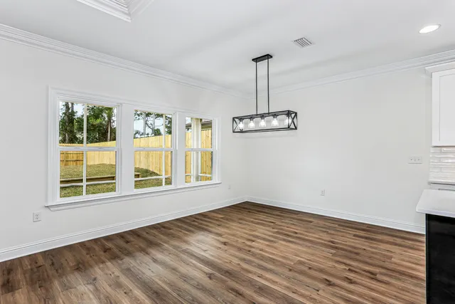 a living room with stainless steel appliances kitchen island granite countertop a stove a refrigerator a sink dishwasher with a dining table and chairs with wooden floor