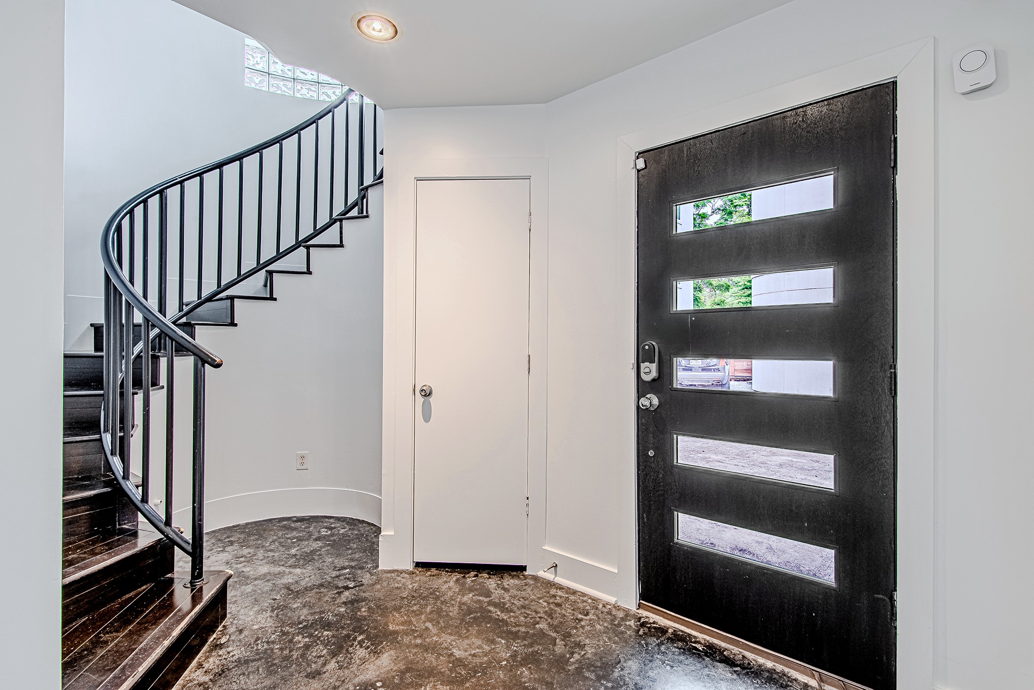 2025 Colquitt Street, Unit E Houston, TX 77098 - Photo 6 of 29 Grand entryway featuring a statement spiral staircase and modern front door design.