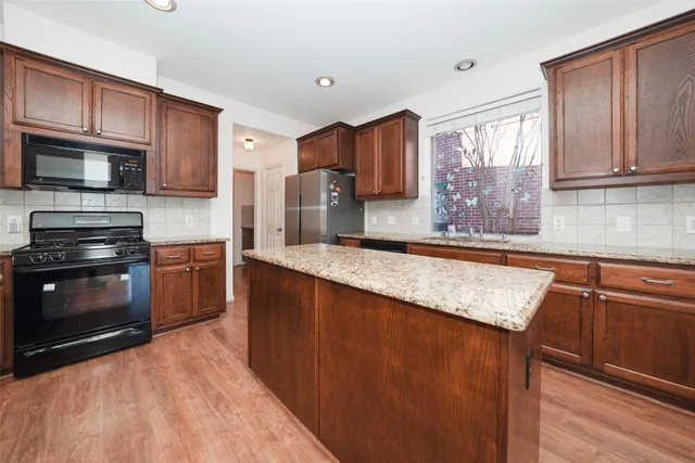 a kitchen with stainless steel appliances granite countertop a stove a sink dishwasher a refrigerator and a microwave oven