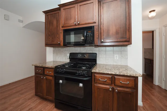 a kitchen with granite countertop wooden cabinets and a stove top oven