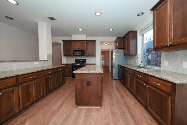 a large kitchen with stainless steel appliances microwave stove and wooden floor