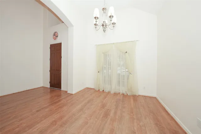 an empty room with wooden floor and hallway
