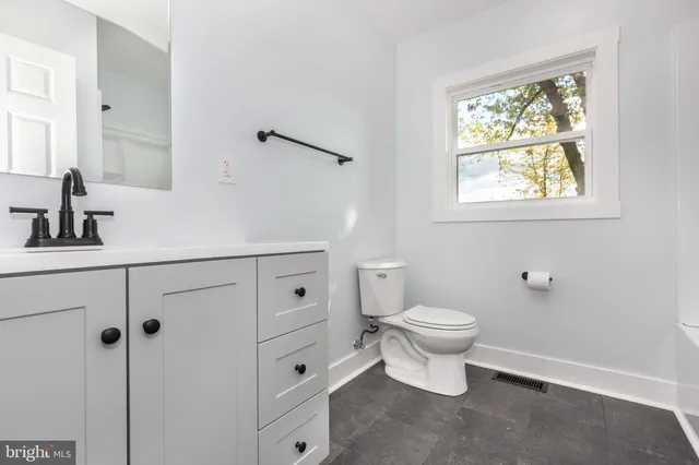 a bathroom with a toilet a sink a window and mirror