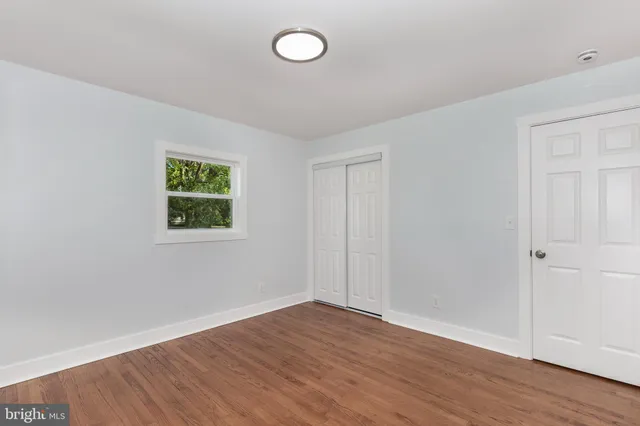an empty room with wooden floor and window