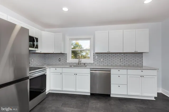 a kitchen with granite countertop white cabinets white stainless steel appliances with a sink and dishwasher