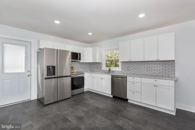 a kitchen with white cabinets stainless steel appliances and window