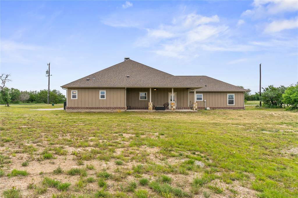 139 Kriston Lane Springtown, TX 76082 - Photo 31 of 39 Expansive rear exterior featuring a covered patio, stone columns, and tan siding