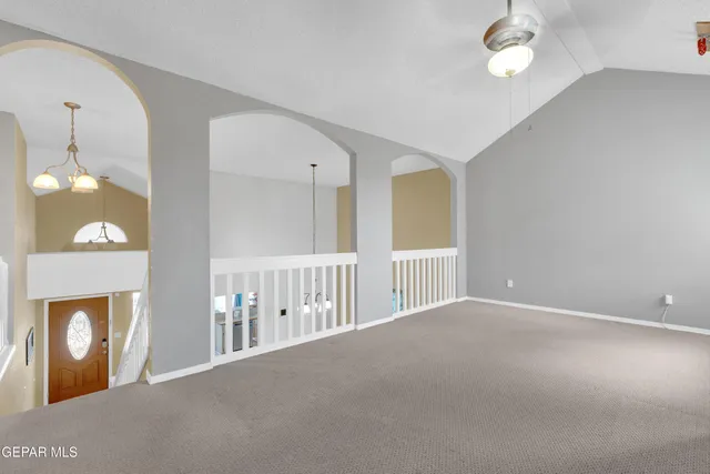 a view of an empty room with a fireplace and a chandelier fan