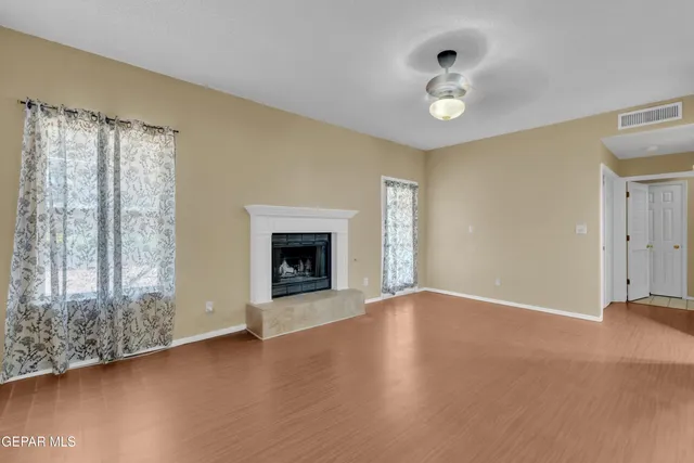 a view of an empty room with window and wooden floor