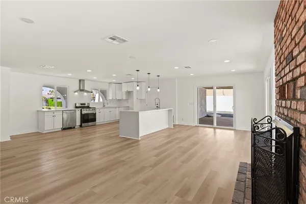a view of a kitchen with kitchen island a sink wooden floor and a counter top space