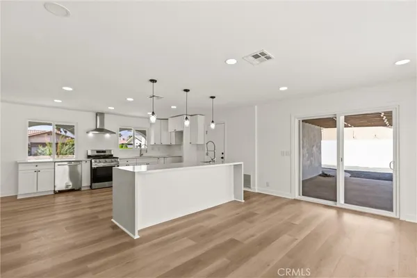 a large kitchen with kitchen island a stove a refrigerator a sink dishwasher with a dining table and chairs with wooden floor