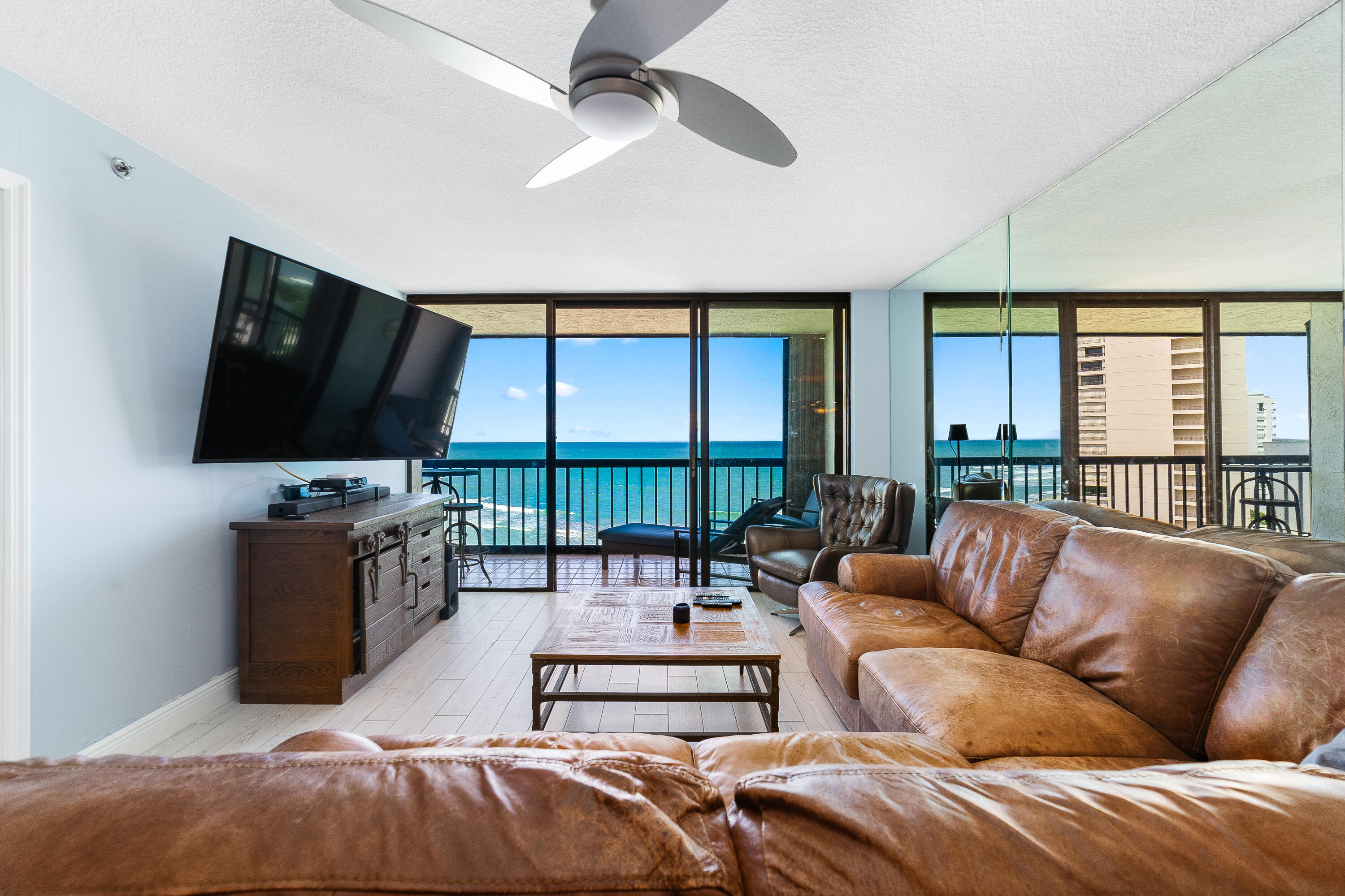 8800 South Ocean Drive, Unit 1102 Jensen Beach, FL 34957 - Photo 6 of 39 a living room with furniture a flat screen tv and a floor to ceiling window