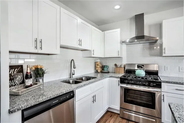 a kitchen with granite countertop a sink stainless steel appliances and white cabinets