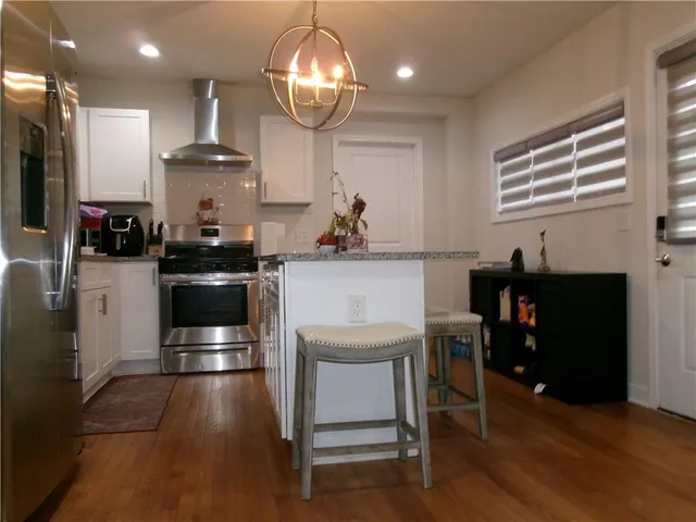 a kitchen with stainless steel appliances a dining table chairs stove and refrigerator