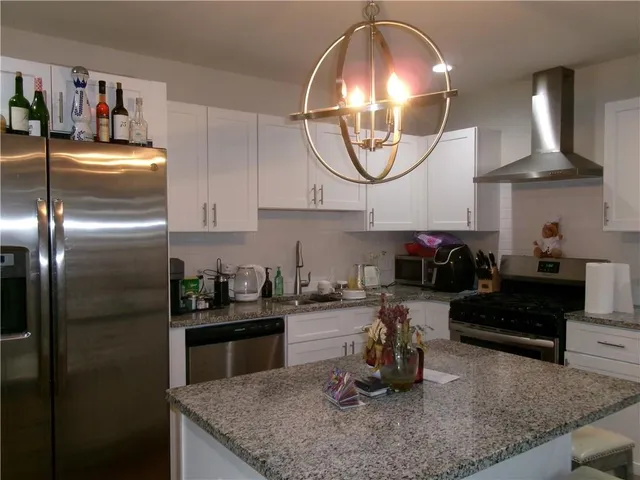 a kitchen with granite countertop a sink a stove and lots of wooden cabinets