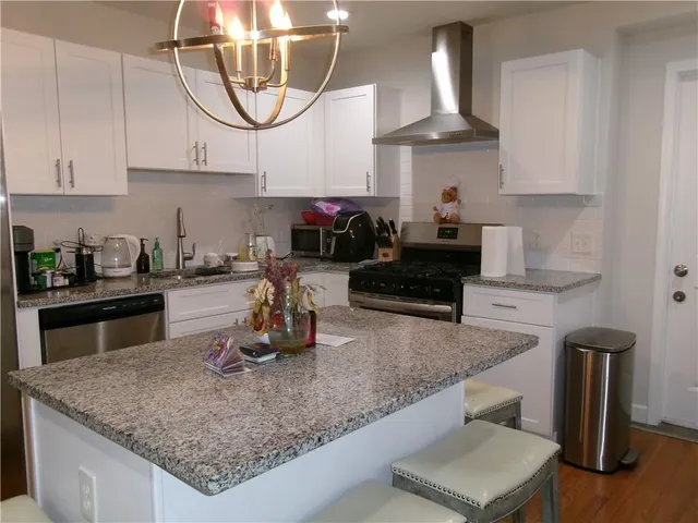 a kitchen with stainless steel appliances granite countertop a sink a stove and a wooden cabinets
