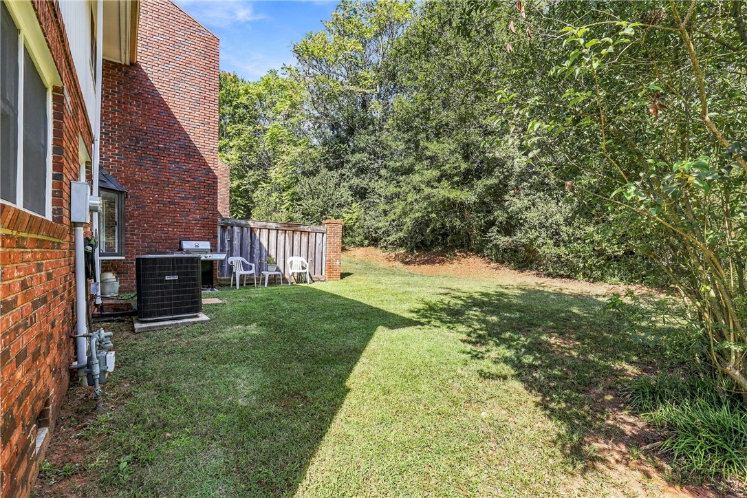 7 Woodbridge Circle Anderson, SC 29621 - Photo 25 of 26 Mature trees frame a grassy lawn bordered by brick and wood fencing.
