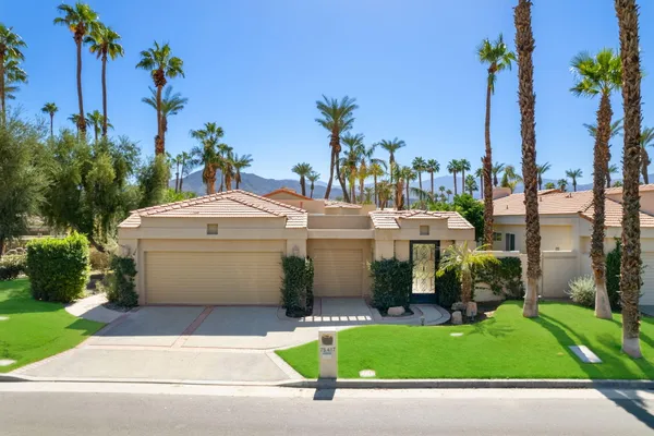 a view of a white house with a yard and palm trees