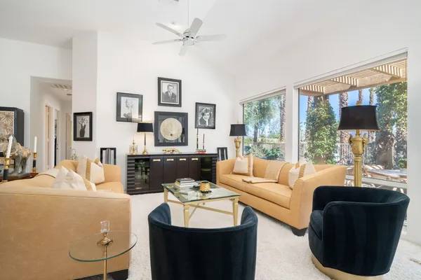 a living room with furniture a rug and wall paintings