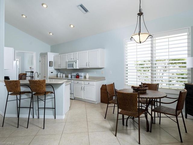 a kitchen with a dining table chairs and white cabinets