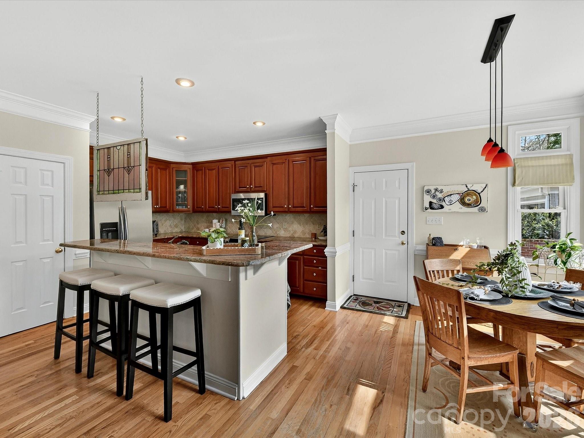 207 Hobbs Street Davidson, NC 28036 - Photo 13 of 40 a kitchen with kitchen island granite countertop wooden floors and wooden cabinets