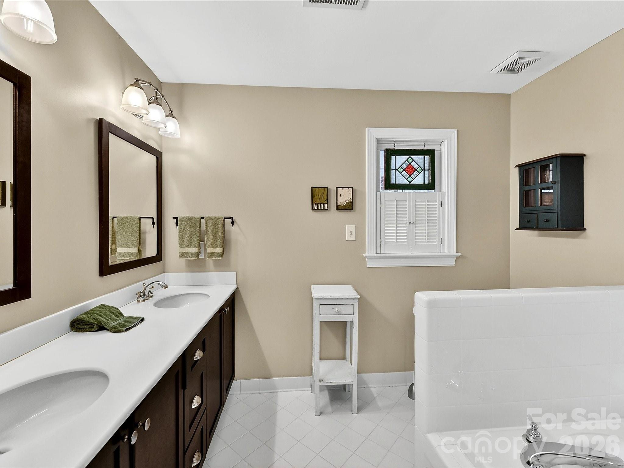 207 Hobbs Street Davidson, NC 28036 - Photo 20 of 40 a bathroom with a granite countertop sink a mirror and a bathtub