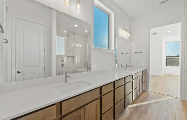 a bathroom with a double vanity sink a toilet and shower