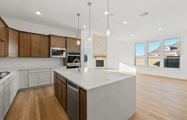 a large kitchen with a stove a sink dishwasher a refrigerator and a oven with wooden floor