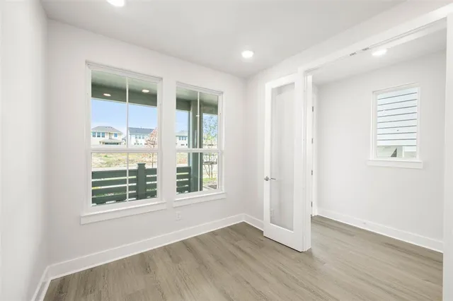 an empty room with wooden floor and windows