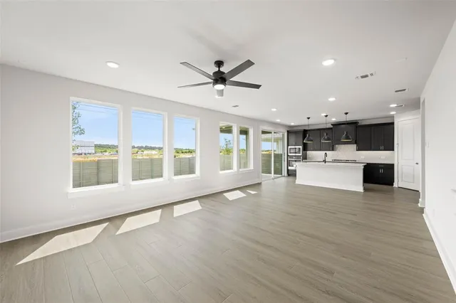 a view of an empty room with a kitchen and wooden floor