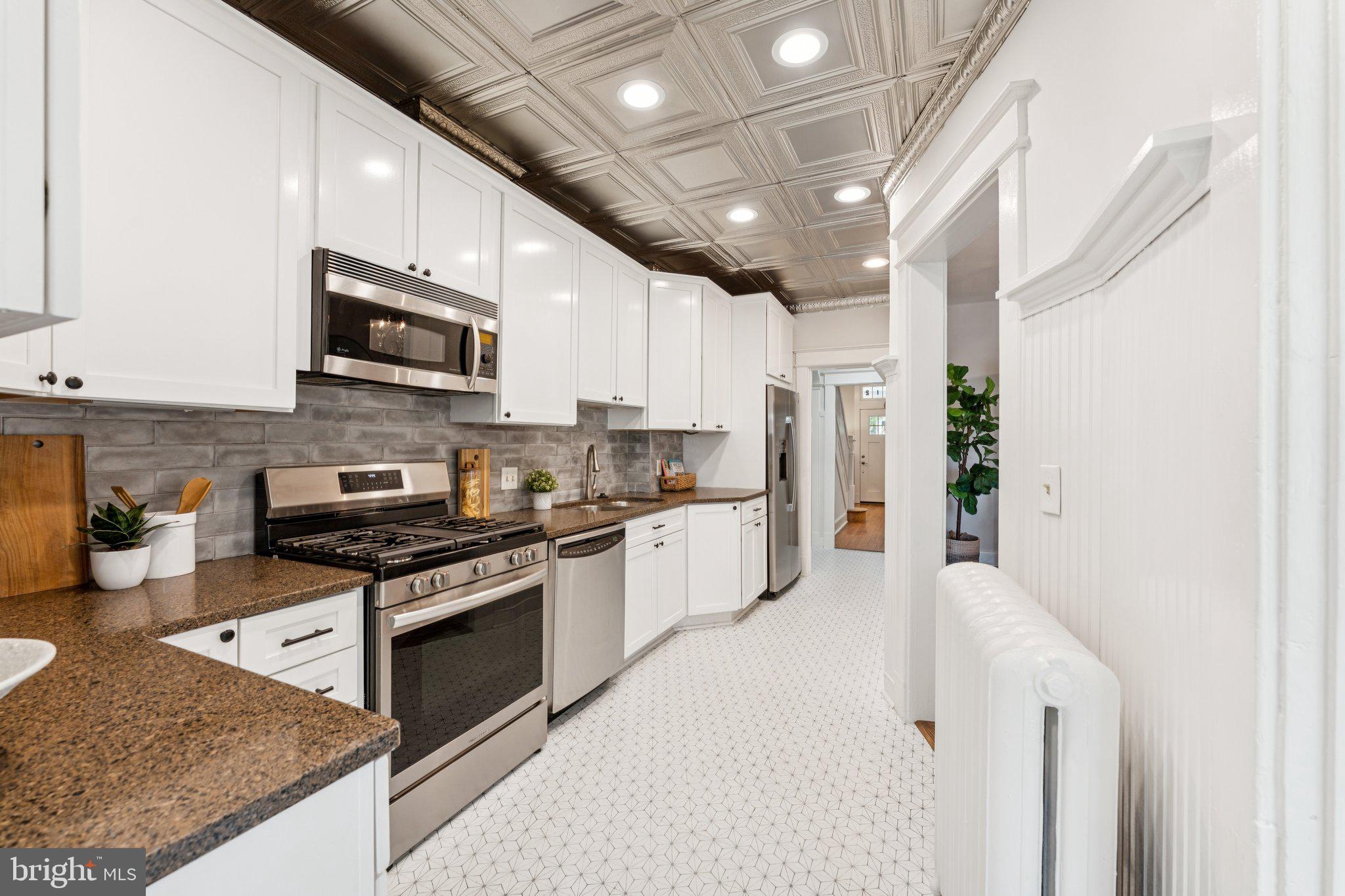 1412 Decatur Street Northwest Washington, DC 20011 - Photo 10 of 36 a large kitchen with stainless steel appliances granite countertop a stove a sink and a microwave