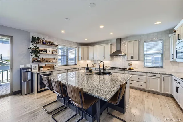 a kitchen with stainless steel appliances granite countertop a stove top oven a sink dishwasher a dining table and chairs with wooden floor