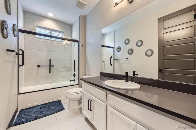 a bathroom with a granite countertop sink a toilet a mirror and shower