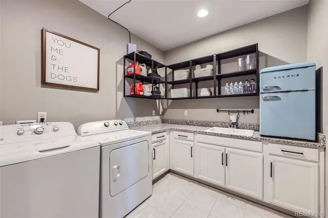 a utility room with stainless steel appliances granite countertop a sink and a cabinets