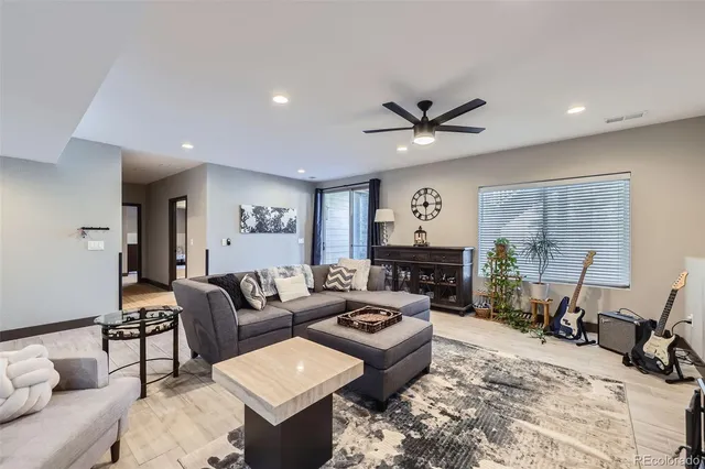 a living room with furniture ceiling fan and a large window