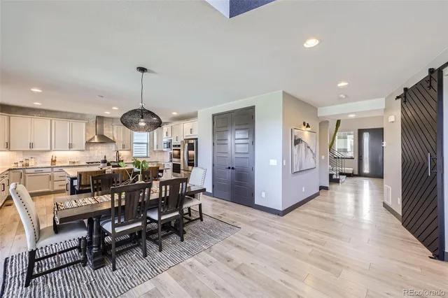 a view of a dining room and livingroom with furniture wooden floor a rug a painting and a chandelier