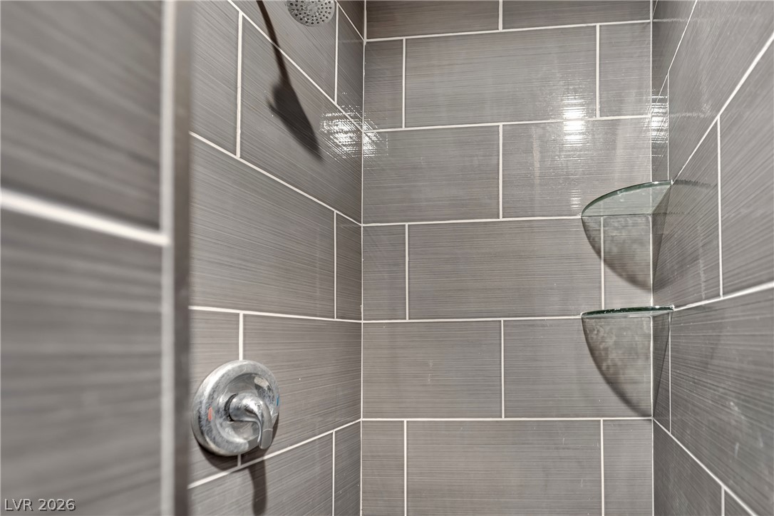 420 North Racetrack Road Henderson, NV 89015 - Photo 25 of 52 Modern shower with sleek gray tile and convenient built-in glass shelving.