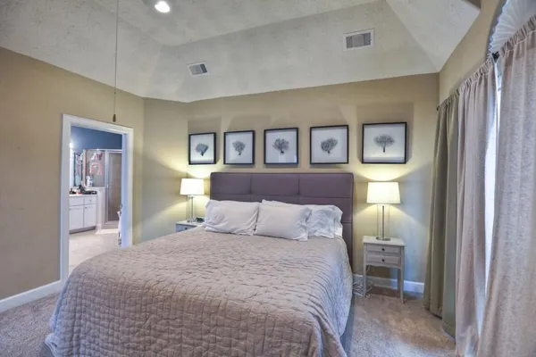 a bedroom with a large bed and painting on the wall