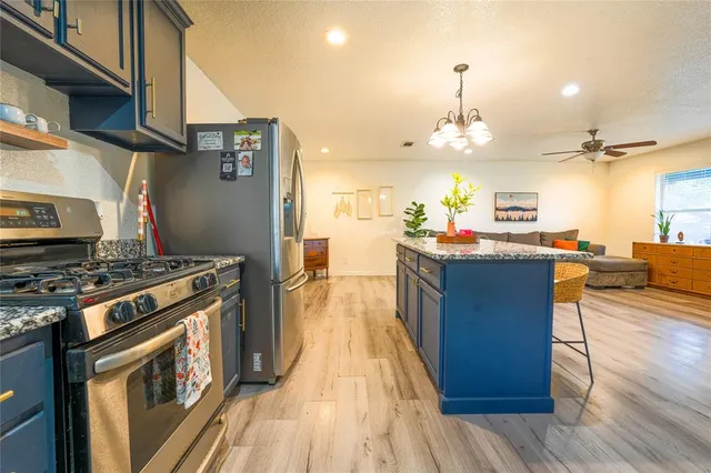 a kitchen with stainless steel appliances granite countertop a stove and a wooden floors