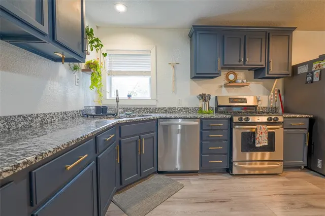 a kitchen with stainless steel appliances granite countertop a stove a sink and a microwave
