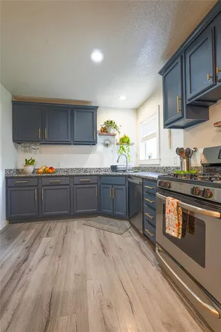 a kitchen with granite countertop a sink cabinets and stainless steel appliances