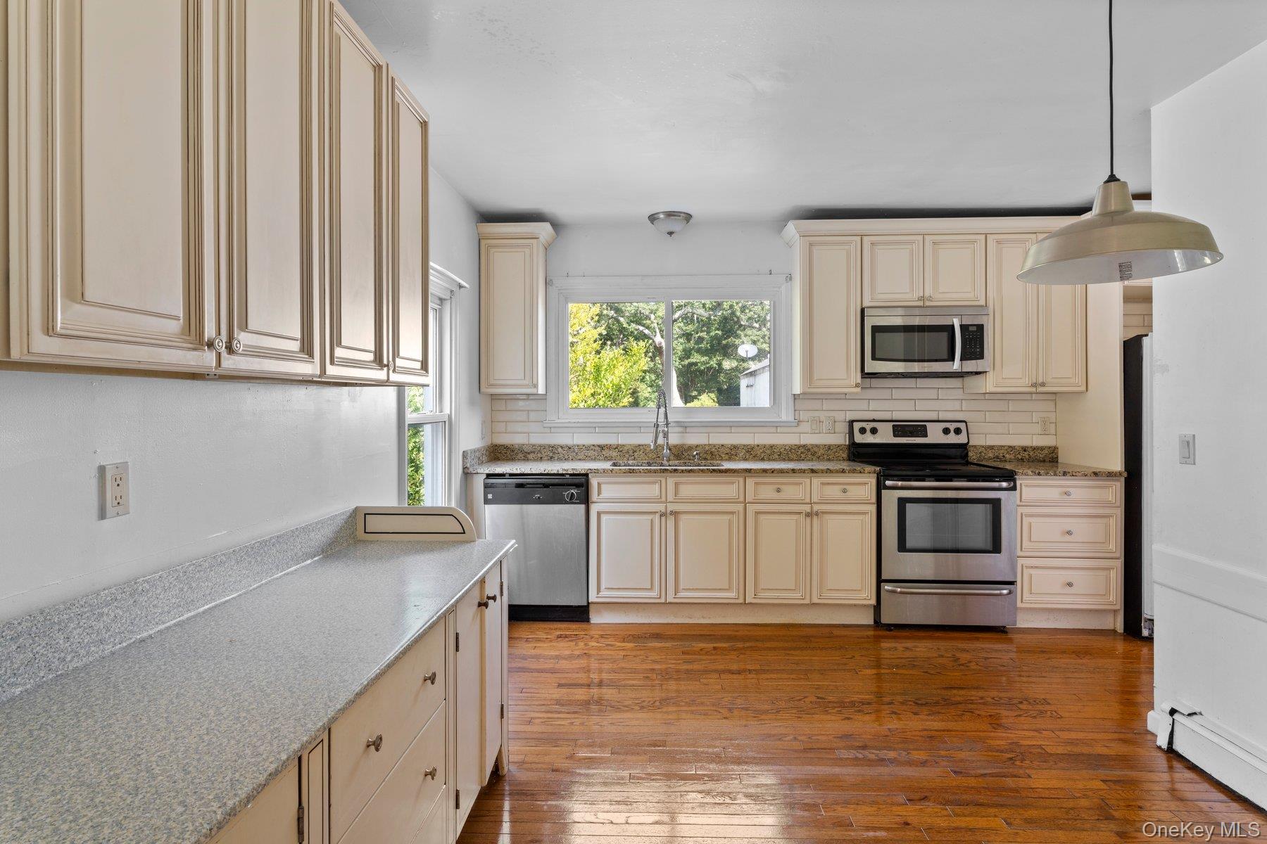39-41 Foster Road Quogue, NY 11959 - Photo 5 of 13 a kitchen with granite countertop a stove a sink and a microwave