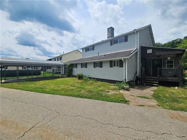 a view of a house with a yard and large trees