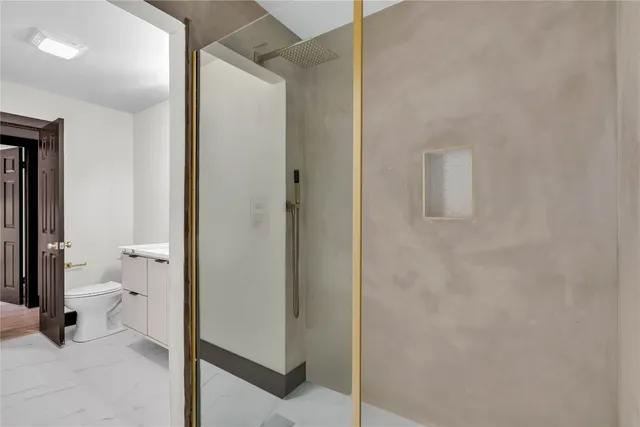a bathroom with a granite countertop toilet and a shower