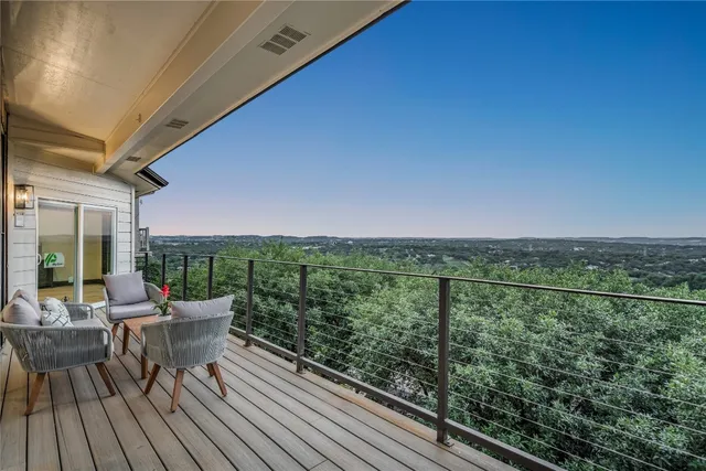 a balcony with wooden floor table and chairs