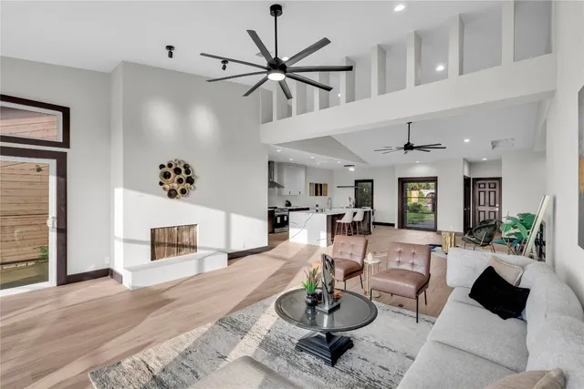 a living room with furniture kitchen view and a wooden floor
